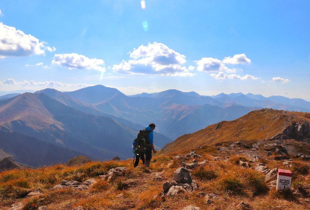 Turysta z dzieckiem na czerwonym szlaku z Krzesanicy na Ciemniak, wrześniowe popołudnie, widok na inne tatrzańskie szlaki