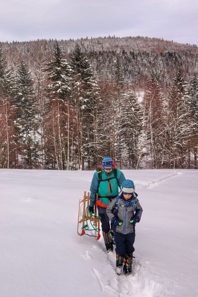 Turysta z dzieckiem na żółtym szlaku na Jałowiec zimą, polana