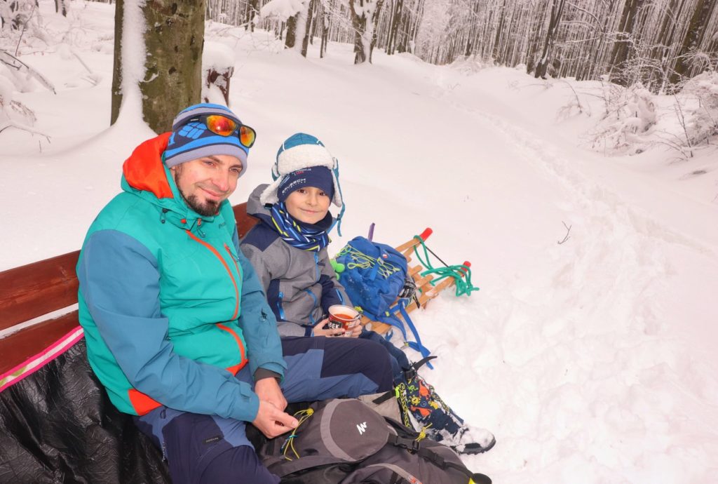 Turysta z dzieckiem odpoczywający na ławce - Polana Krawcowa w drodze na Jałowiec, zima