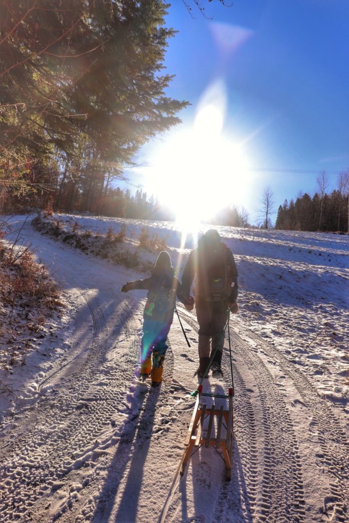 Turysta z dzieckiem, pnąca się w górę zaśnieżona droga, zimowe słońce