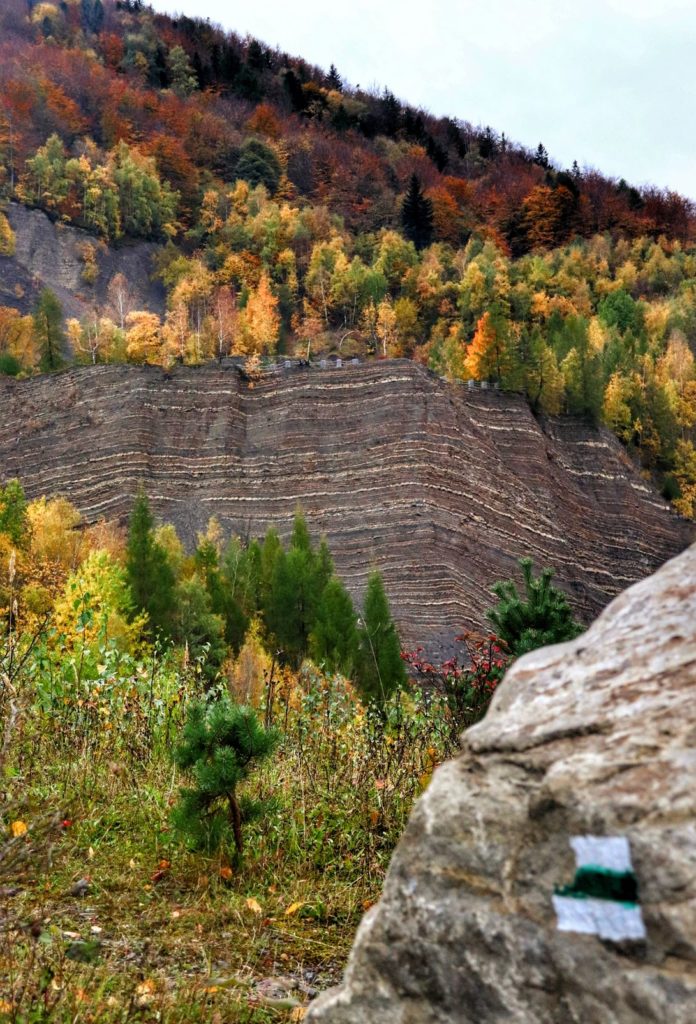 Beskid Mały, skała, na której oznaczony jest szlak zielony - w tle ściana - Kamieniołom w Kozach, jesień