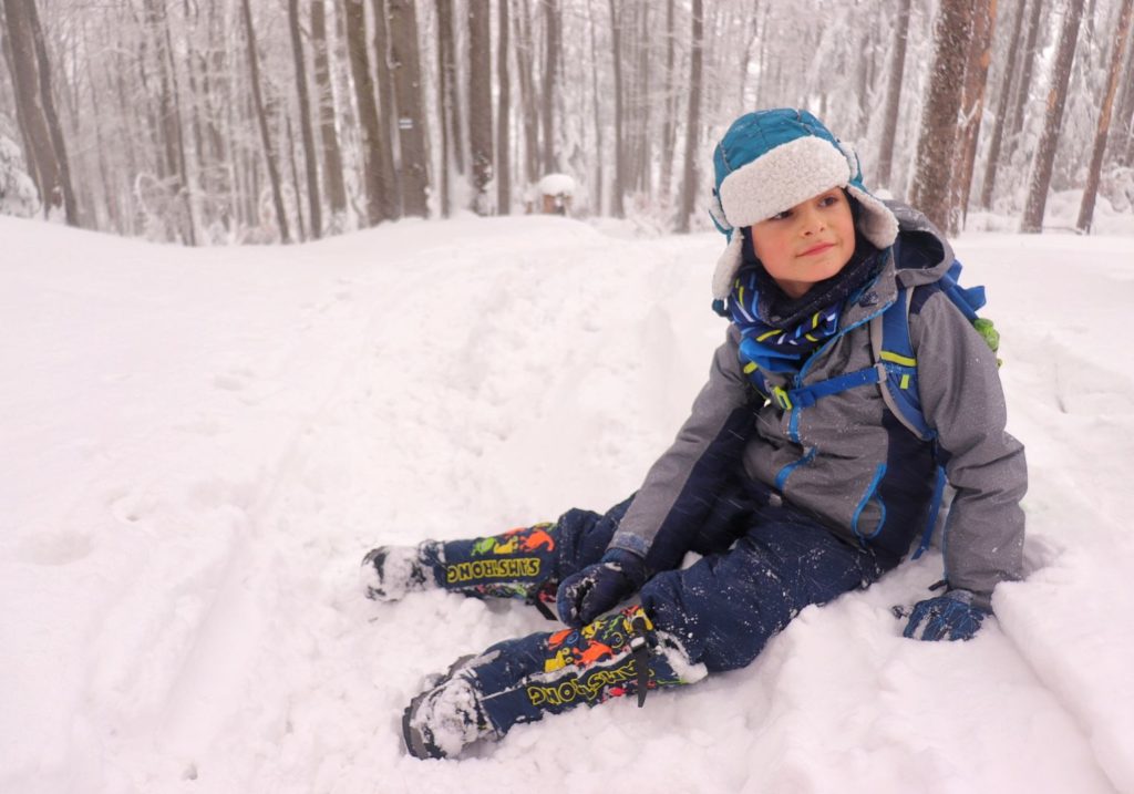 Dziecko odpoczywające na śniegu na górskim szlaku, zimowy las
