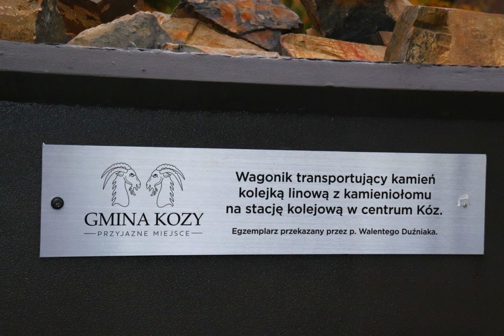 Kamieniołom w Kozach - tabliczka oraz wagonik transportujący kamień kolejką linową z kamieniołomu na stację kolejową w centrum Kóz - GMINA KOZY