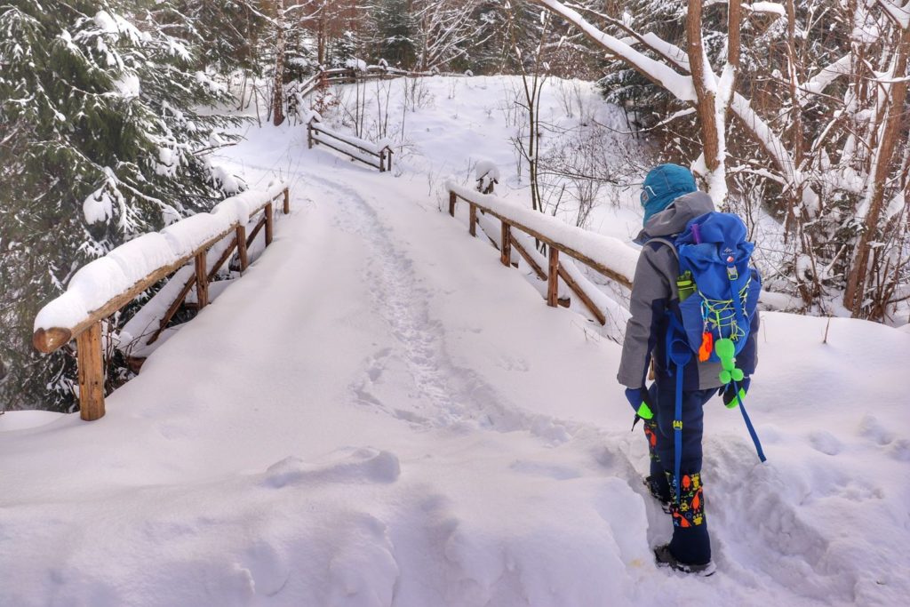 Mały turysta - dziecko wchodzące na drewniany most zasypany przez śnieg - żółty szlak na Jałowiec