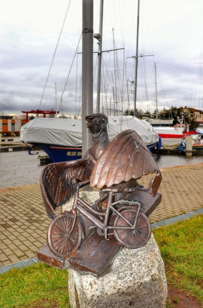 Rzeźba mewy wsiadającej na rower - Marian wsiadający na rower - stojąca w Porcie Jachtowym w Kołobrzegu