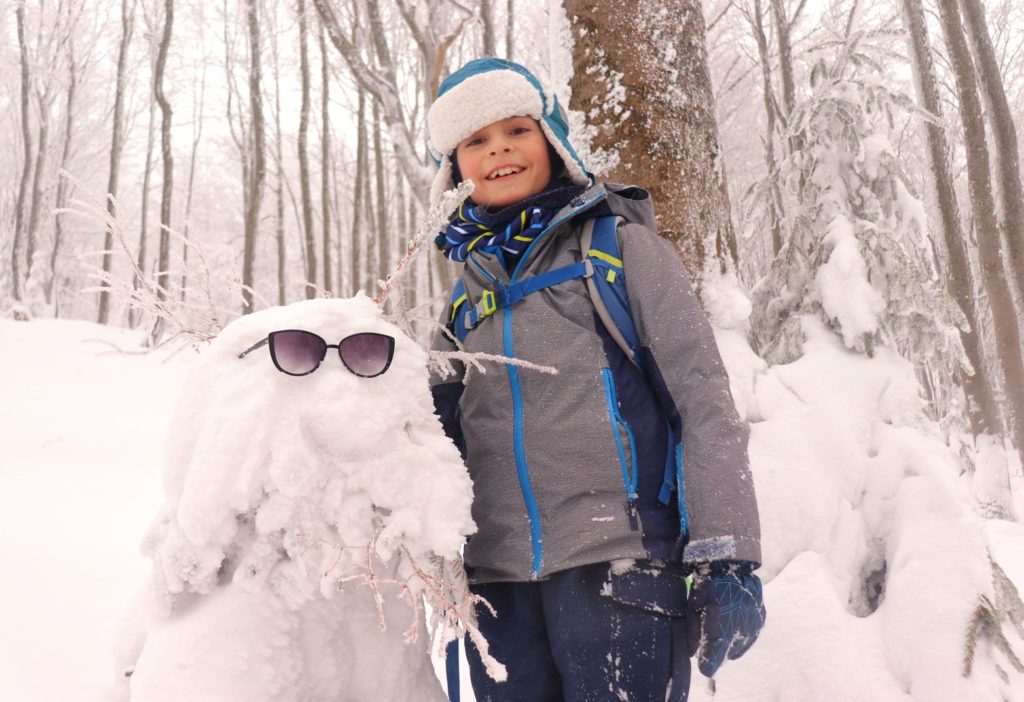 Szczęśliwe dziecko stojące przy leśnym stworze - zima
