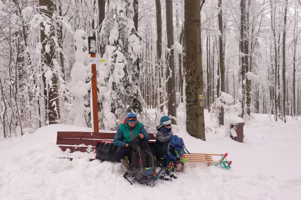 Turysta z dzieckiem odpoczywający na drewnianej ławce - Polana Krawcowa zimą