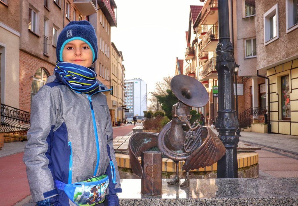 Uśmiechnięte dziecko stojące obok rzeźby mewy w Kołobrzegu - Marian Wolontariusz WOŚP