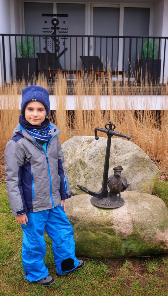 Zadowolone dziecko stojące przy rzeźbie Mariana kapitana - Podczele - Kołobrzeg