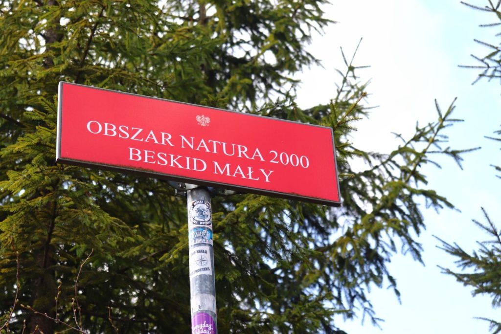 Pozioma czerwona tablica z napisem OBSZAR NATURA 2000 BESKID MAŁY