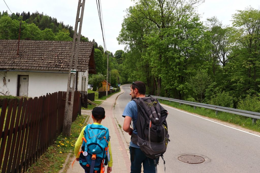 Turysta z dzieckiem na zielonym szlaku idącym do Wąwozu Homole - Jaworki, droga, zabudowania