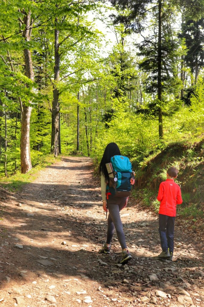 Turystka z dzieckiem na niebieskim szlaku w Porąbce, słoneczny dzień, las