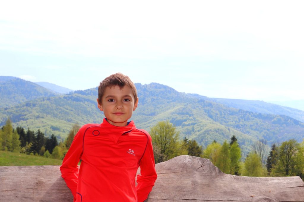 Uśmiechnięte dziecko na szczycie Trzonka w Beskidzie Małym, w tle krajobraz górski
