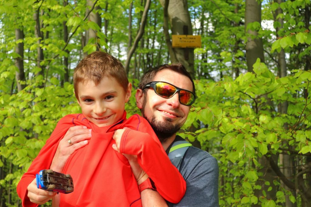 Uśmiechnięty turysta z dzieckiem na szczycie Trzonka w Beskidzie Małym