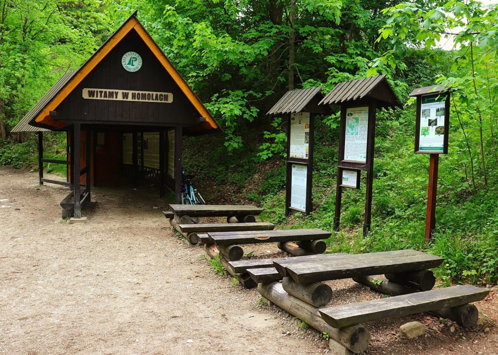 Wejście do Rezerwatu przyrody Wąwóz Homole, drewniane ławki, tablice informacyjne oraz drewniana kasa