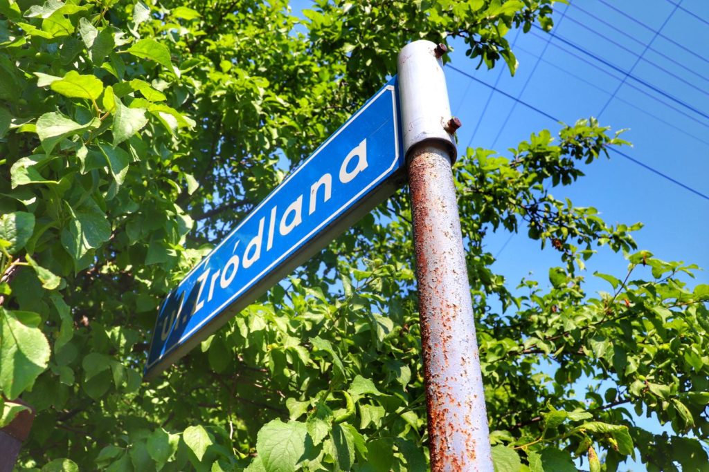 Niebieska tablica z białym napisem - nazwa ulicy w Żarnówce Małej - ulica Źródlana