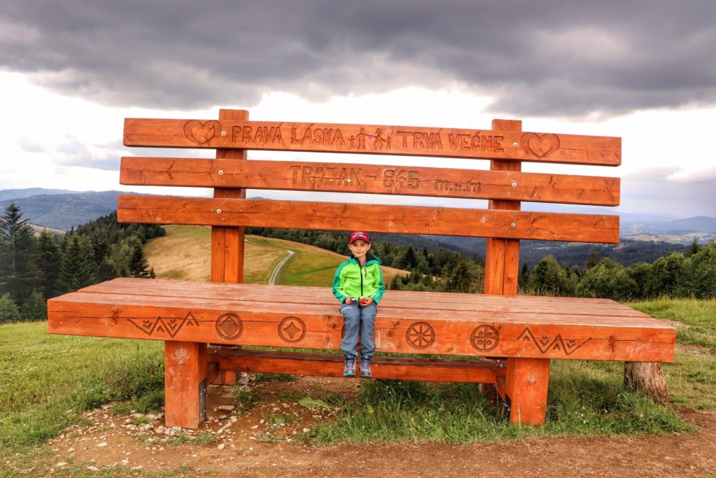 Kykula - Trojak - szczyt na Słowacji, wielka drewniana ławka, na której odpoczywa zadowolone dziecko