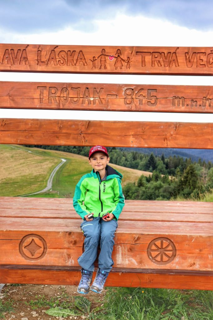 Uśmiechnięte dziecko odpoczywające na wielkiej drewnianej ławce - szczyt Kykula