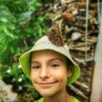 Uśmiechnięte dziecko w kapeluszu, na którym siedzi motyl Caligo memnon, motylarnia w Jarosławcu