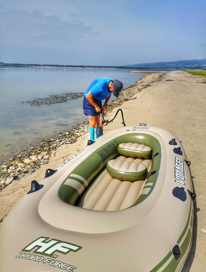 Mężczyzna pompujący ponton na brzegu Jeziora Czorsztyńskiego