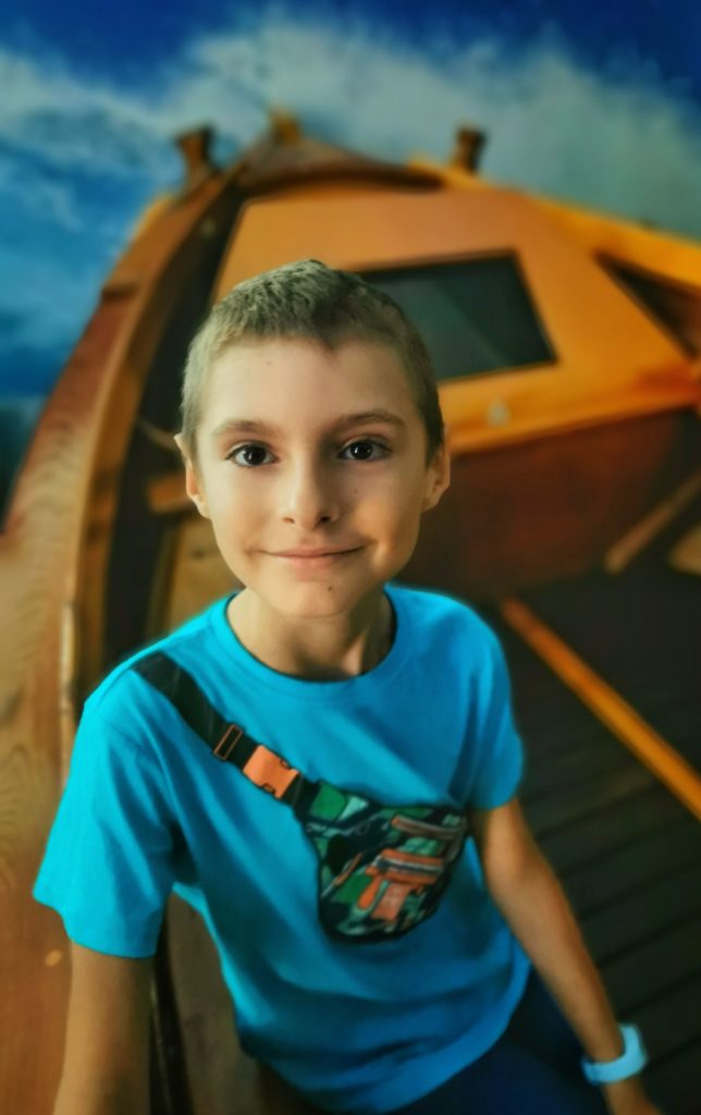 Zadowolone dziecko siedzące w drewnianej łodzi - Muzeum Fauny i Flory Morskiej i Śródlądowej w Jaworzu koło Bielska-Białej
