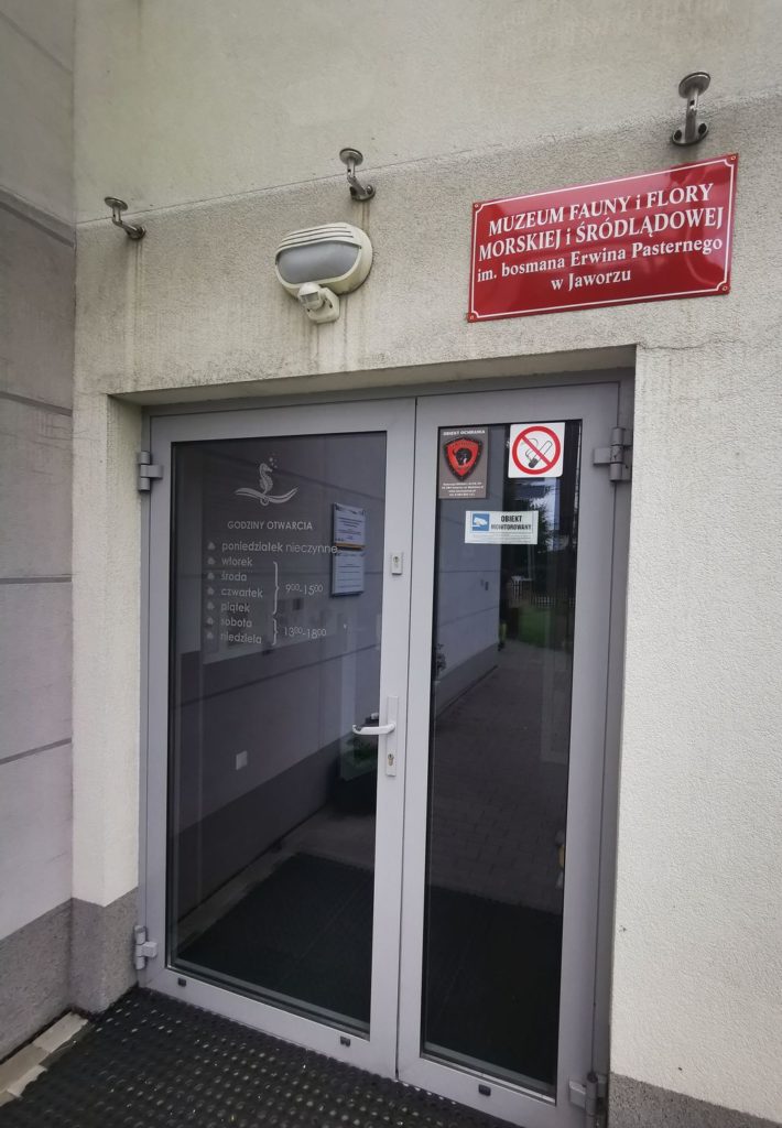 Wejście do Muzeum Fauny i Flory Morskiej i Śródlądowej w Jaworzu, czerwona tabliczka wisząca nad drzwiami