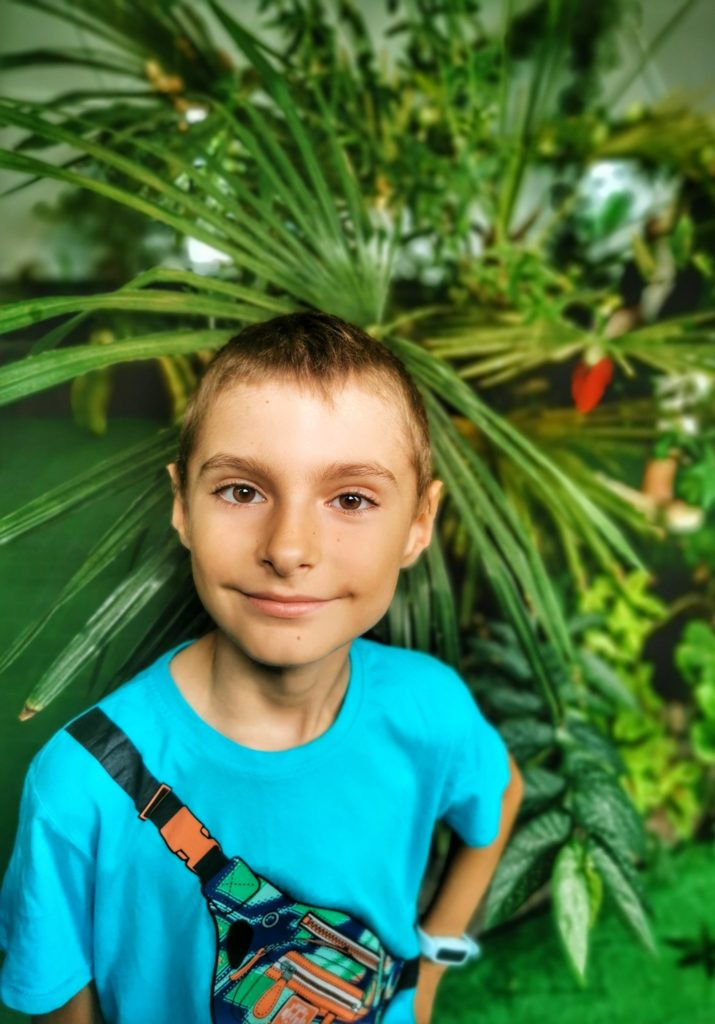 Zadowolone dziecko na tle zielonych roślin w motylarni w Jaworzu