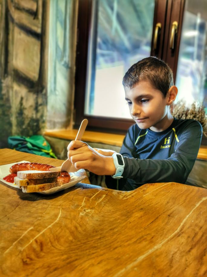 Dziecko jedzące pieczoną kiełbaskę w schronisku na Trzech Kopcach Wiślańskich w Beskidzie Śląskim