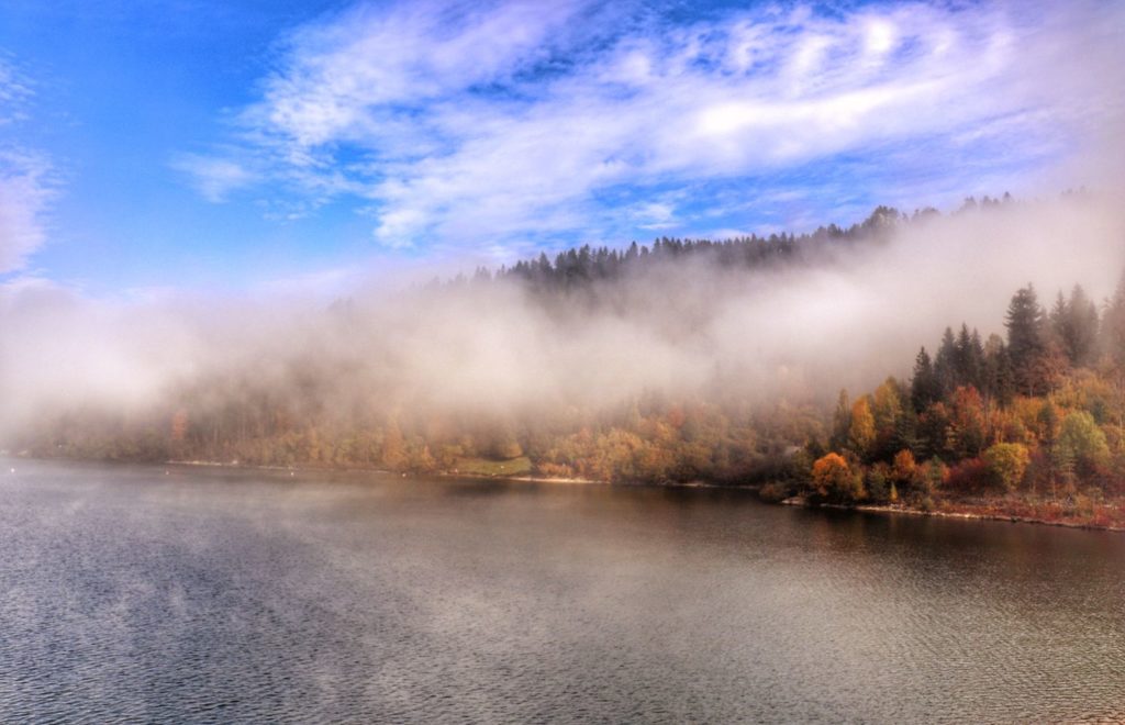 Poranne mgły nad Jeziorem Czortyńskim, jesienne drzewa, niebieskie niebo