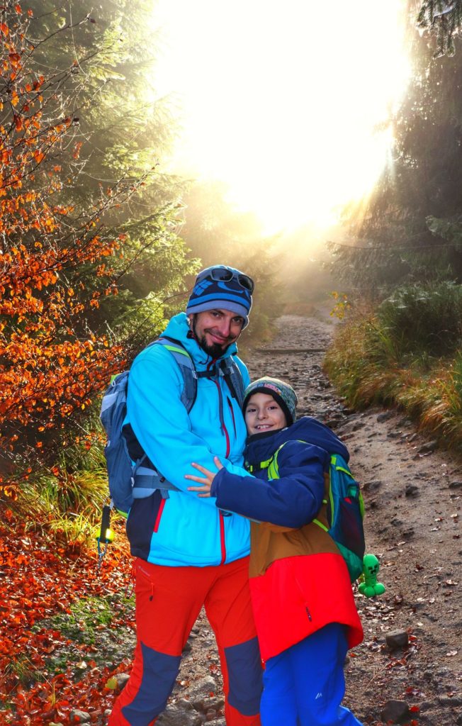Uśmiechnięci turyści - mężczyzna z dzieckiem na szlaku czerwonym idącym z Przełęczy Salmopolskiej na Malinowską Skałę, jesienny poranek, beskidzki las