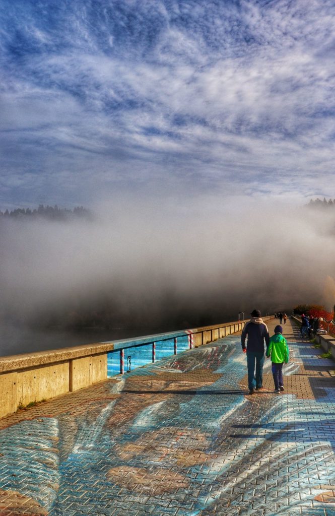 Zapora Niedzica 3D, poranne mgły, turysta z dzieckiem spacerujący po zaporze w Niedzicy