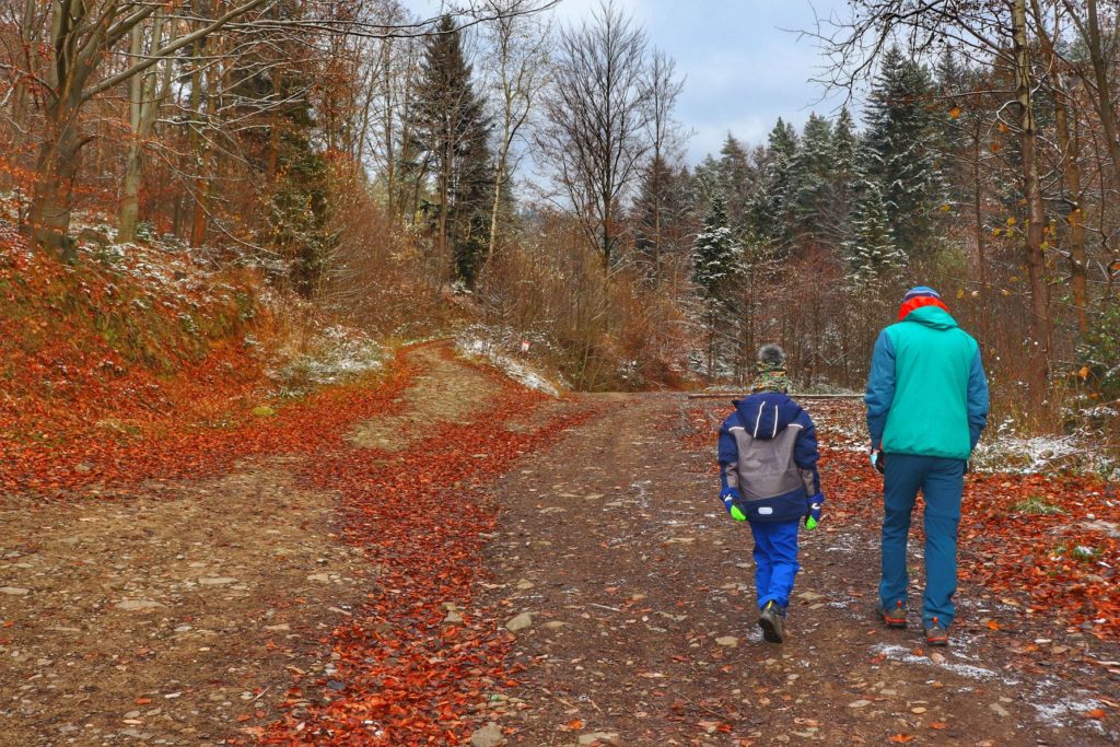 Turysta z dzieckiem, szeroka droga na czarnym szlaku w Bielsku, jesień
