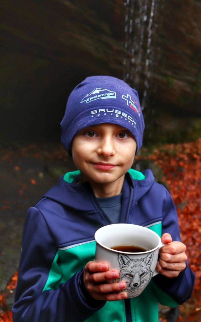 Uśmiechnięte dziecko z kubkiem ciepłej herbaty w Beskidzie Małym