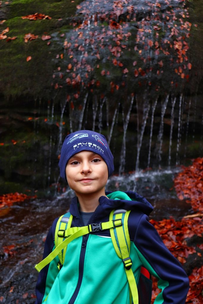 Zadowolone dziecko w lesie Beskidu Małego - w tle Wodospad Dusiołek