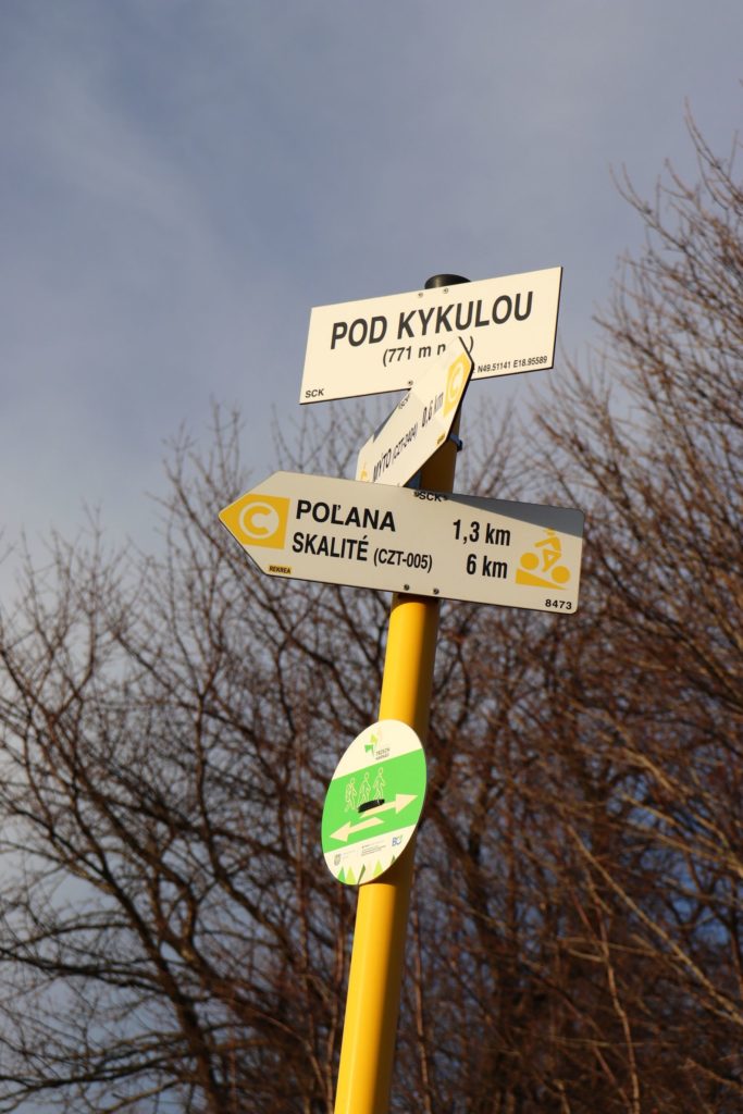 Biała tabliczka - Pod Kykulou - szlak czerwony pieszy, szlak żółty rowerowy - drogowskaz