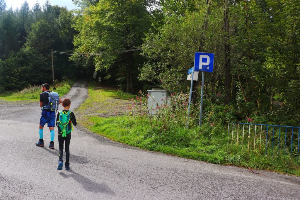 Turysta z dzieckiem przechodzący przez drogę na ulicę Pilarzy - zielony szlak w Brennej Leśnica