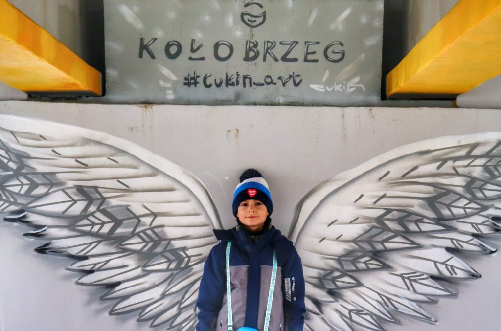 Uśmiechnięte dziecko, dolny pokład molo w Kołobrzegu, mural - skrzydła mewy