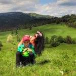 Turystka z dzieckiem siedząca na obszernej polanie w Pieninach - Biała Woda - okolice