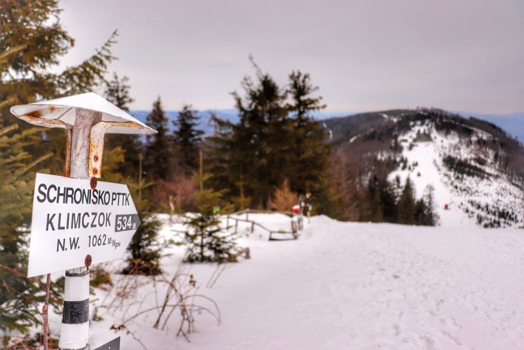 Szczyt Klimczok w Beskidzie Śląskim, biała tabliczka wskazująca kierunek do Schroniska Klimczok, zima