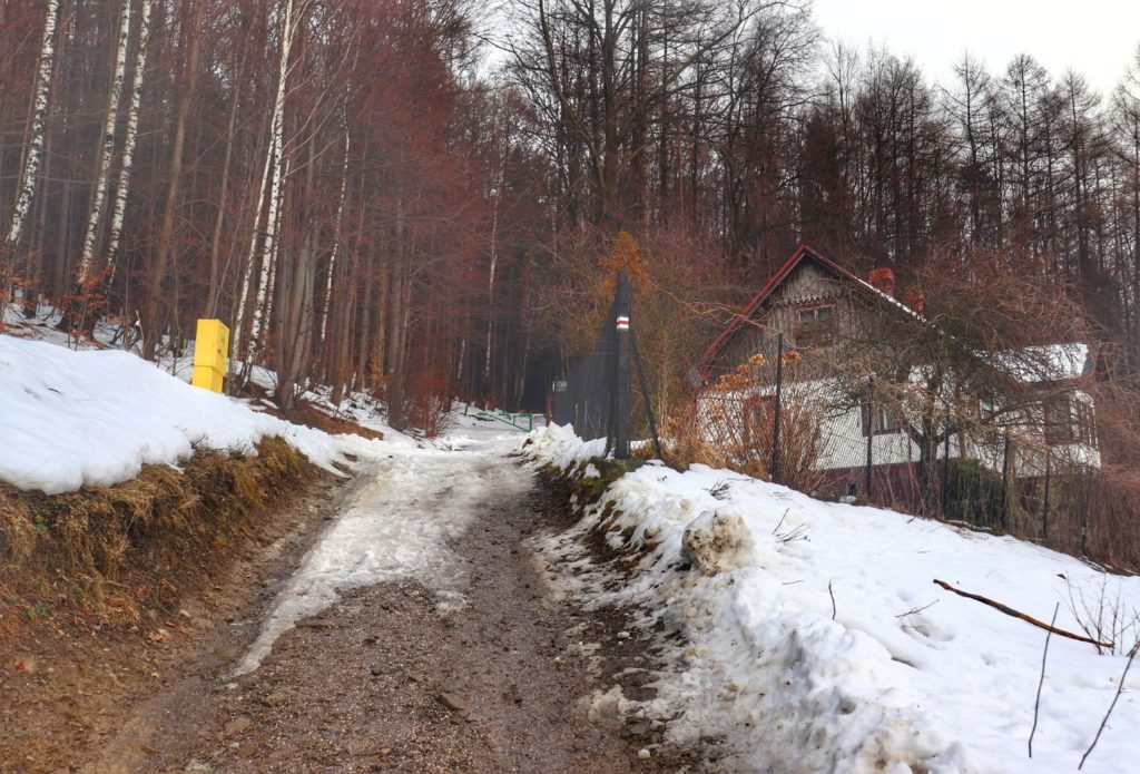 Szeroka błotnista droga na szlaku czerwonym - Bystra Śląska, ostatni na szlaku dom, szlaban, las
