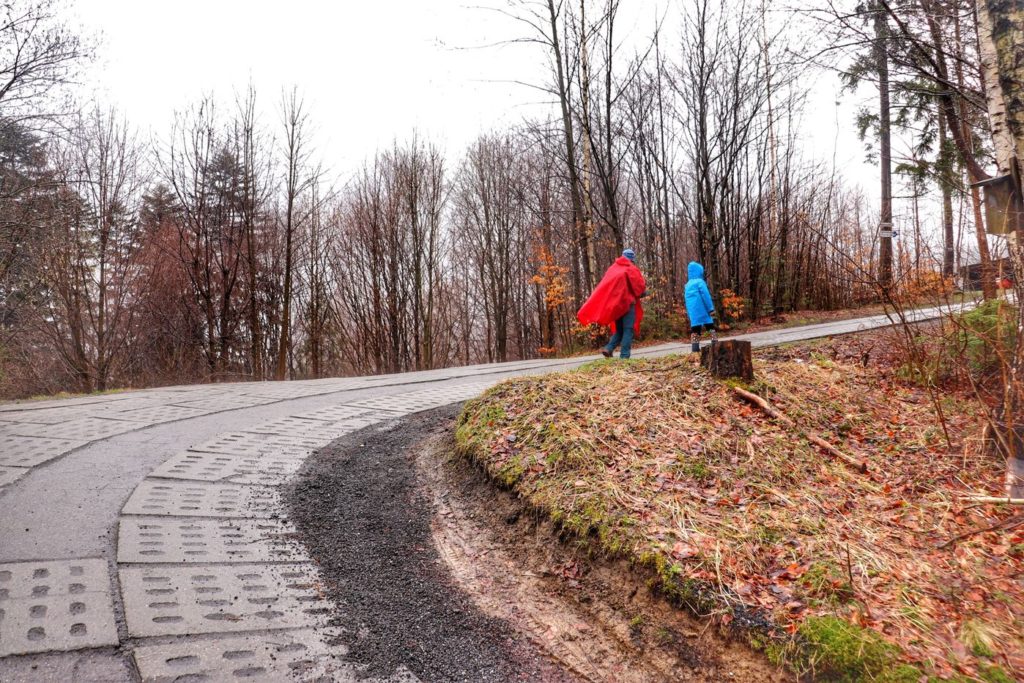 Szeroka droga betonowa skręca ostro w prawo - Wisła Jawornik, turysta z dzieckiem