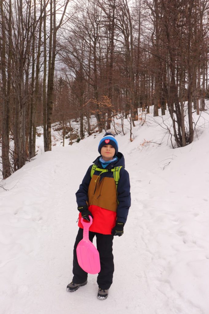 Uśmiechnięte dziecko na leśnej zaśnieżonej drodze