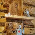 Drewniany zegar z pułkami, na których leżą pluszowe zabawki - miś, sowa wiszące w schronisku pod Dubraszką