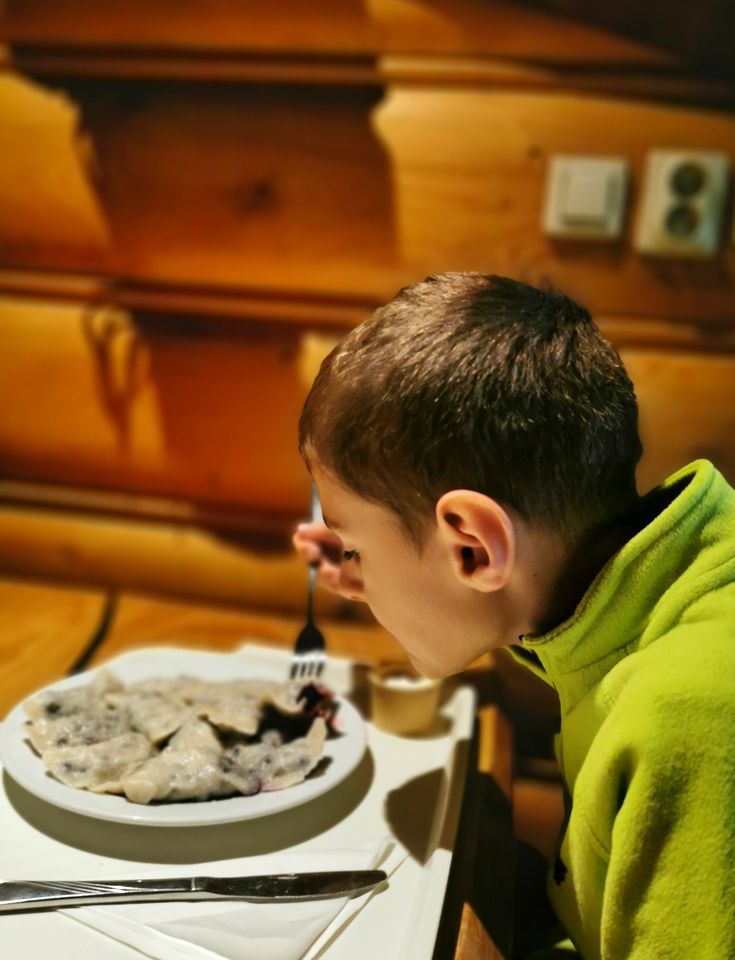 Dziecko jedzące pierogi z borówkami w schronisku pod Durbaszką