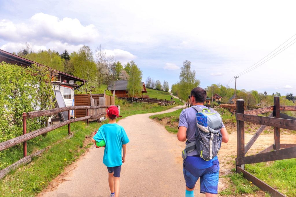 Dziecko z tatą idące szeroką drogą asfaltową do punktu widokowego Ścieszków Groń, ulica Szczytowa - Łysina