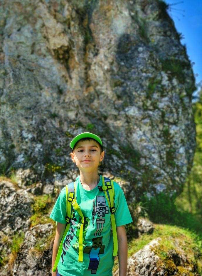 Uśmiechnięte dziecko w Pieninach Spiskich pozujące na tle skały - Lorenocwe Skałki