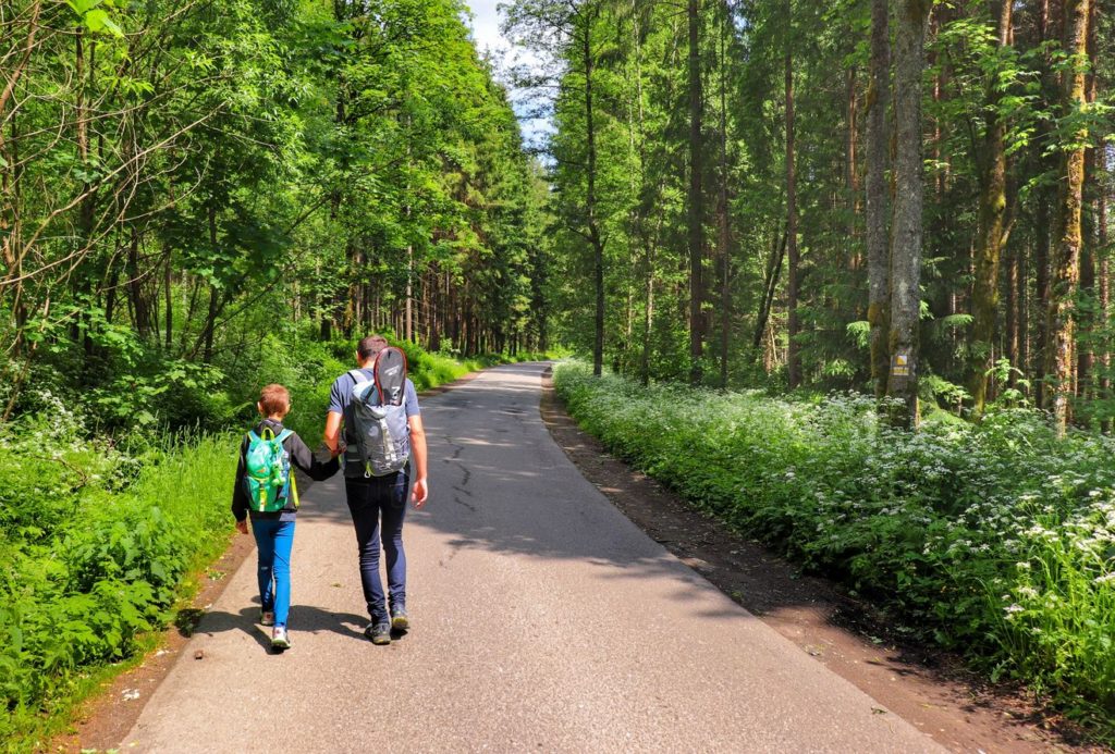 Turysta z dzieckiem na żółtym szlaku w Istebnej, szeroka droga asfaltowa, las
