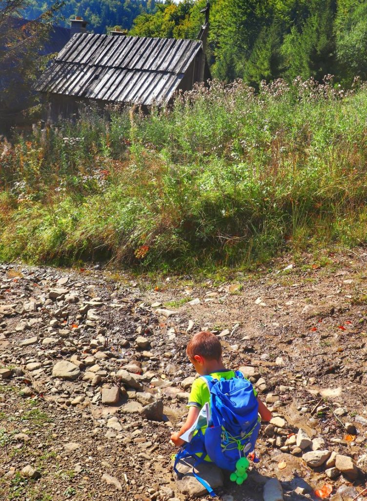 Dziecko odpoczywające na trasie na Magurki, kamieniste podejście, stara, drewniana chata, gorczańska polana