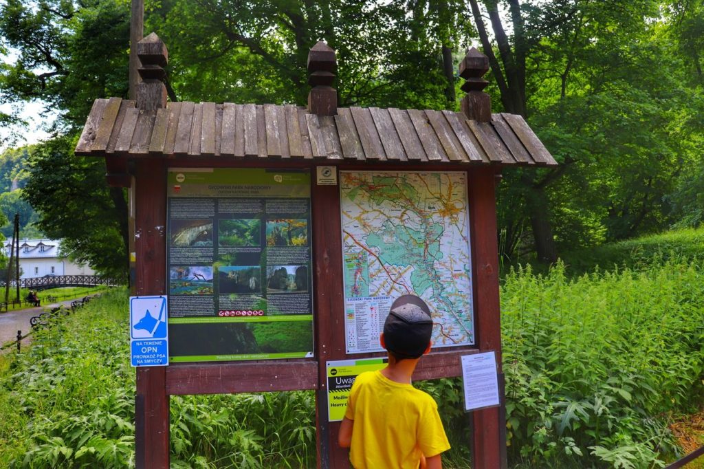 Dziecko, tablica informacyjna i mapa Ojcowskiego Parku Narodowego