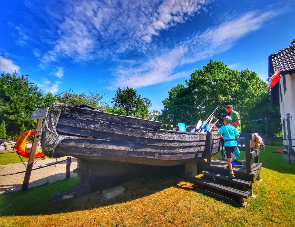 Eksponat, stara drewniana łódź, turysta z dzieckiem w Galerii Rybackiej w Jezierzanach